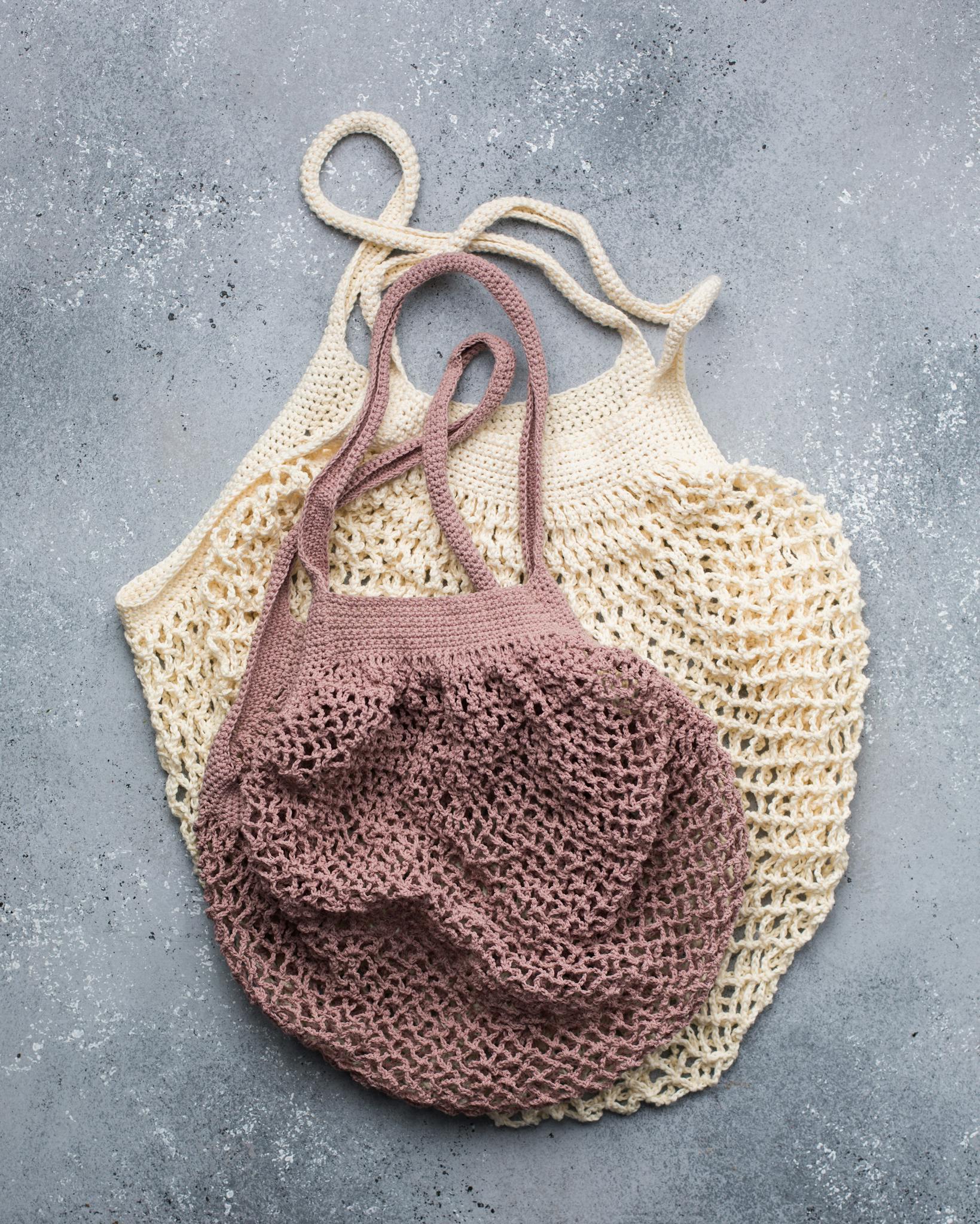 Two knitted reusable mesh bags in beige and pink, ideal for eco-friendly shopping.